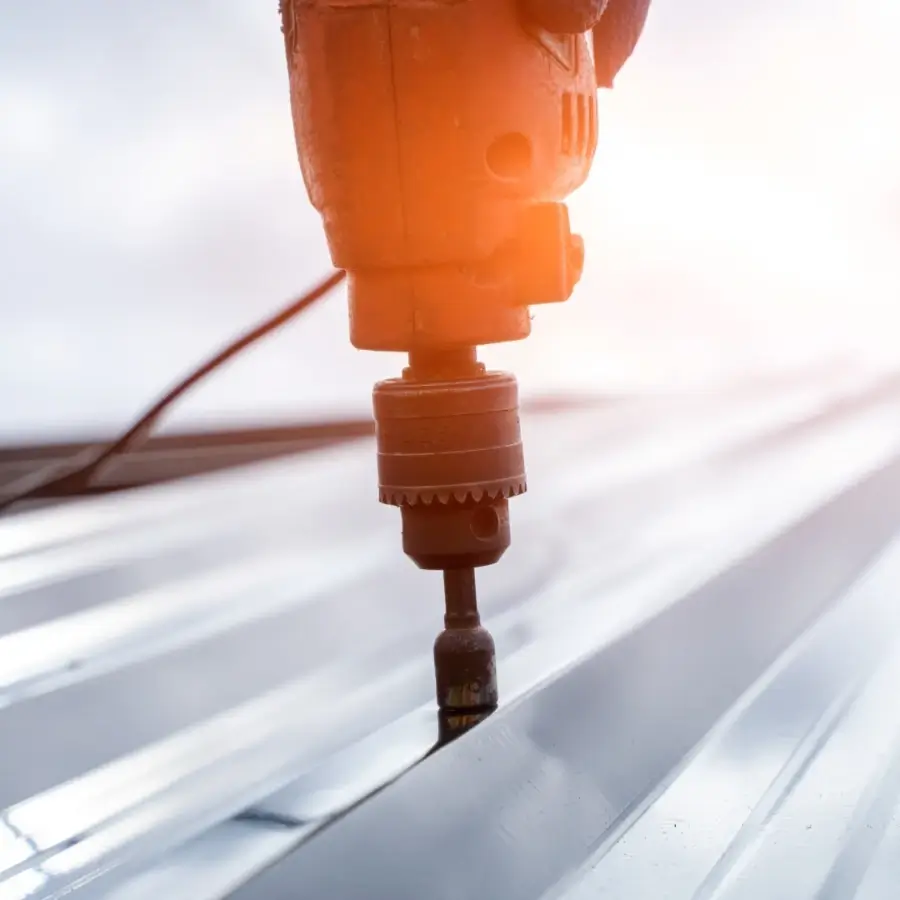 Roofing contractor installing a screw into a standing seam metal roof panel during installation in Muskoka